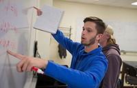 Physics student works on a problem at the white board.